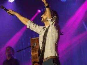 Jay Parrino performing on stage with microphone and guitar