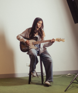 Anika Joshi seated playing electric guitar