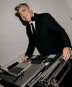 DJ Brett Martin in a suit at the DJ decks