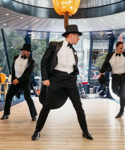Tap dancers in top hats and tails performing at an event